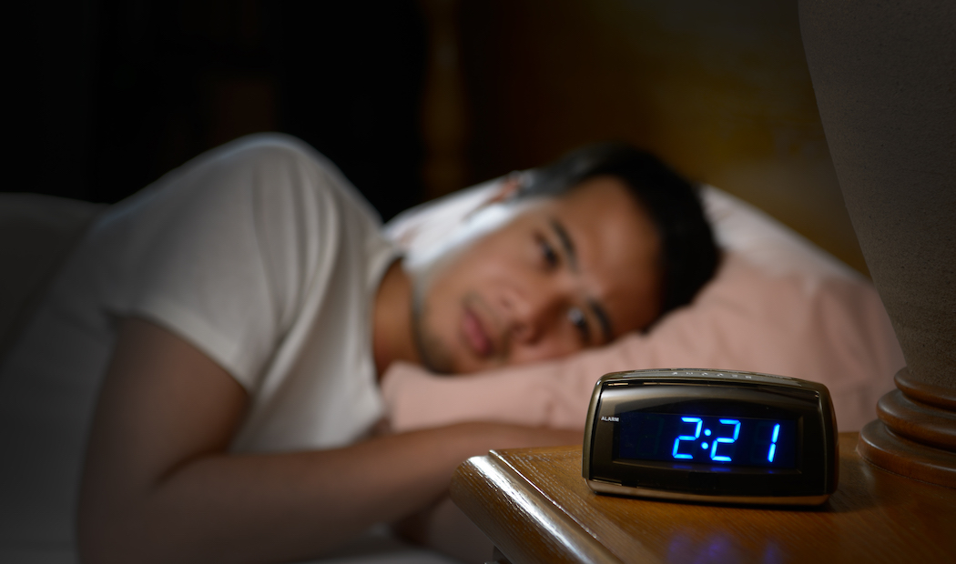 Depressed man suffering from insomnia lying in bed